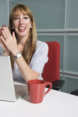 A teacher smiles over her laptop